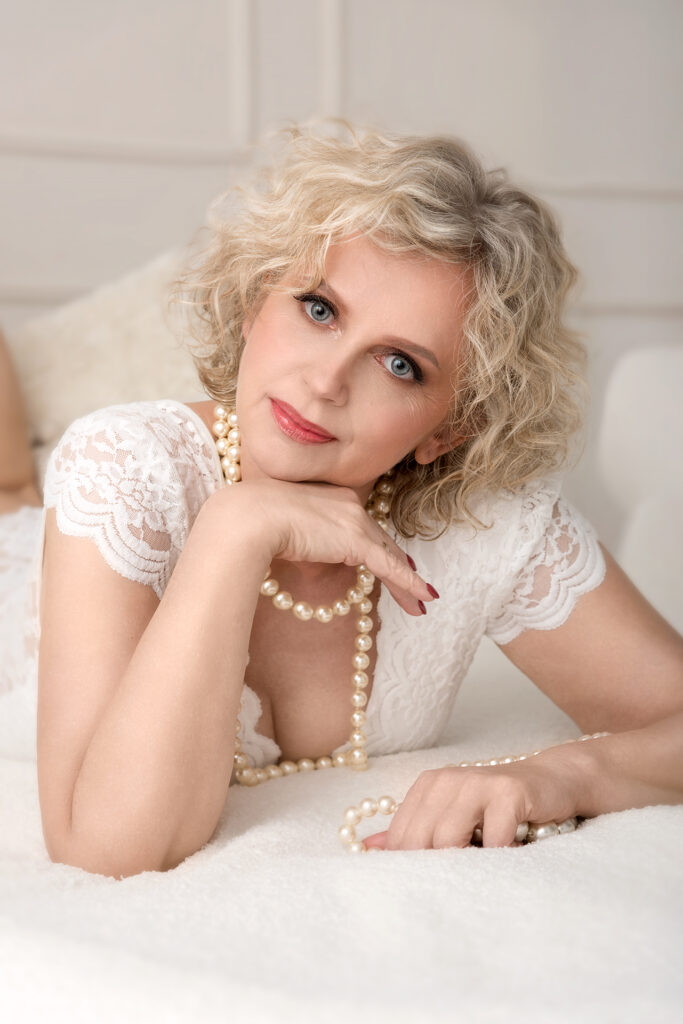 elegancka blondynka leży na łóżku w bieli, kobieca sesja zdjęciowa w warszawie